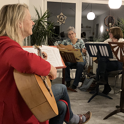 Gitarrenlehrerin im Unterricht mit Seniorinnen